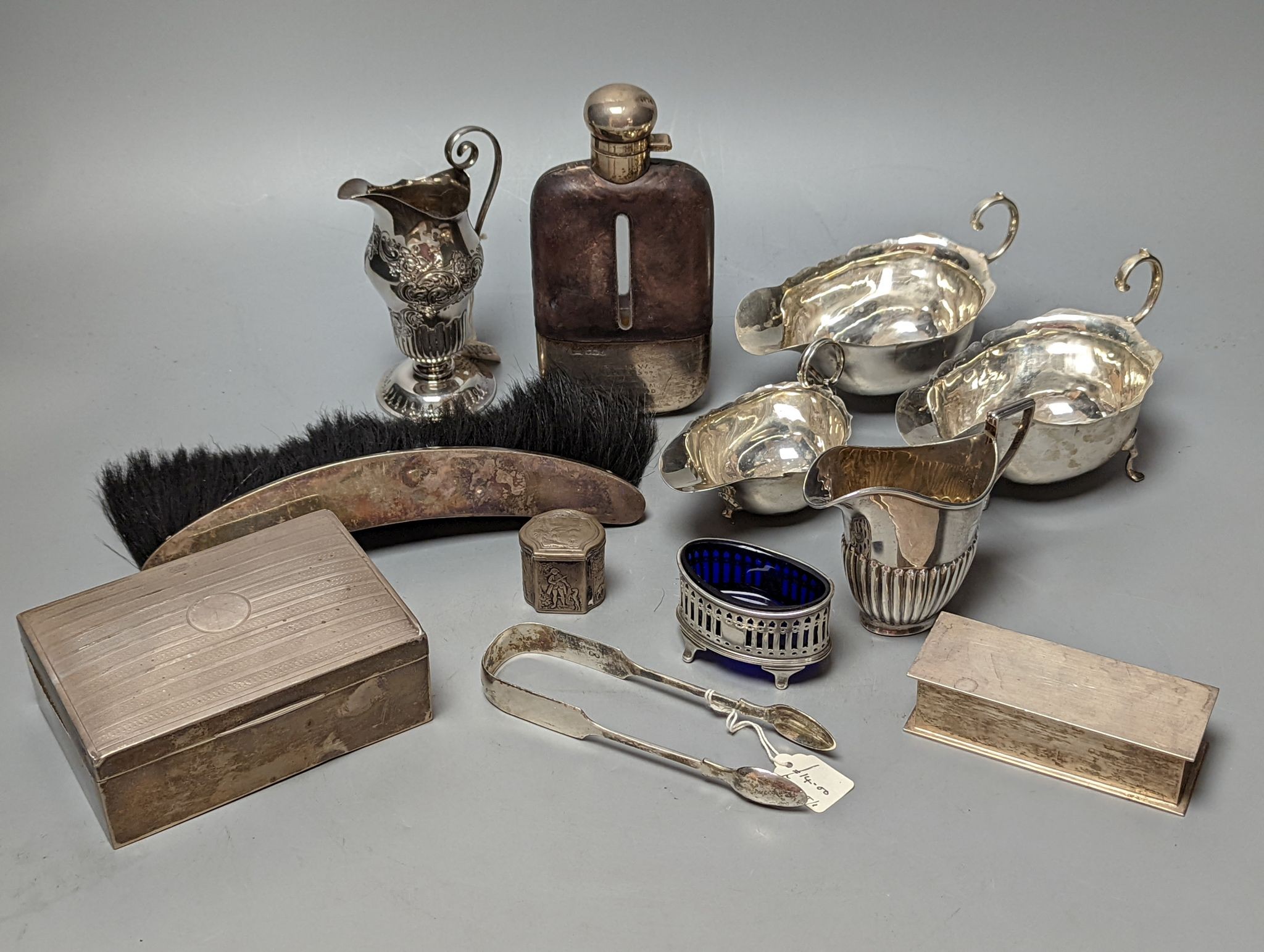 A group of assorted silver items including George V silver mounted hip flask(bruise), a pair of silver sauceboats(a.f.) one other sauceboat, sterling box, two silver cream jugs, cigarette box, salt, sugar tongs, brush an